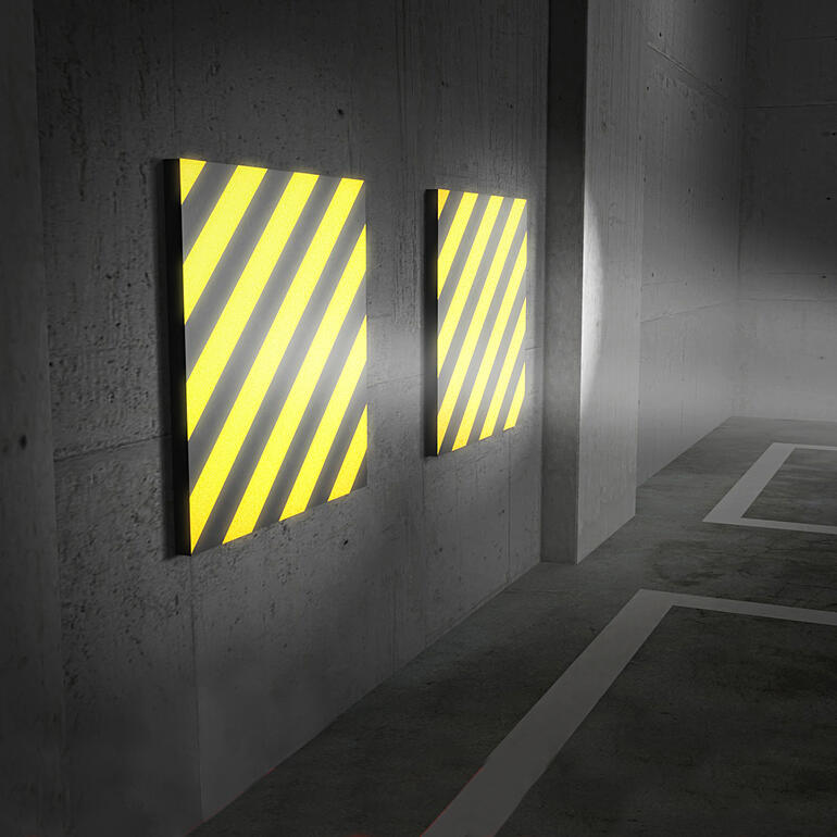 La lumière incidente se reflète très clairement sur les bandes de couleur jaune et noire : un véritable plus en matière de sécurité lorsque vous vous garez. Deux coussins de mur de garage avec des rayures jaune-noires contre un mur.