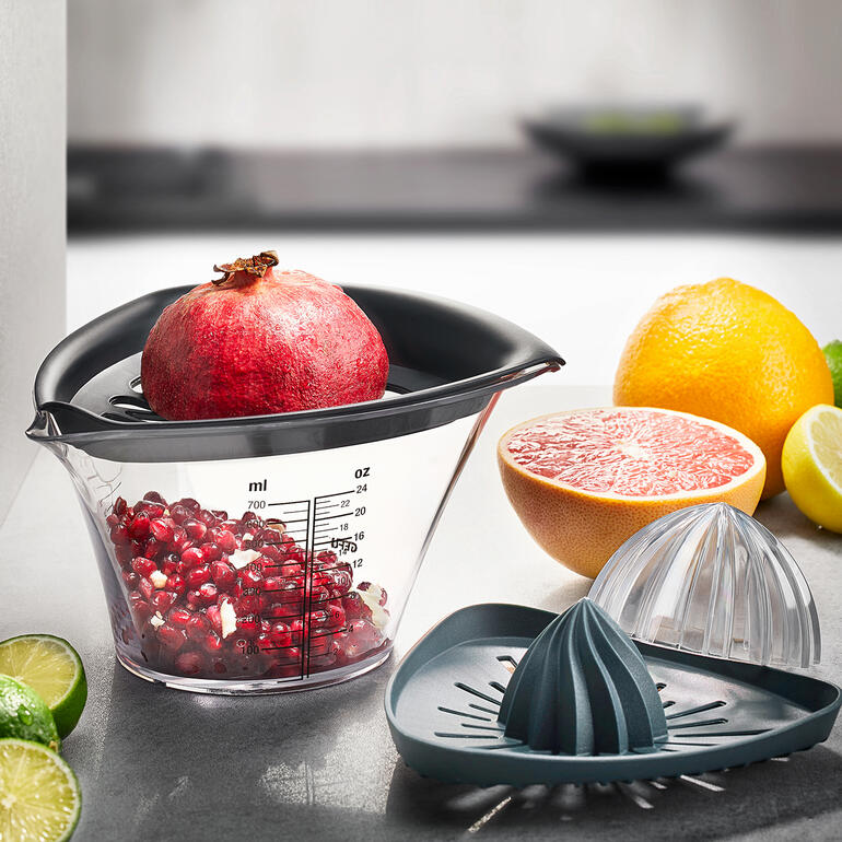 Extracteur de graines de grenade et presse-agrumes Gefu avec une grenade et des agrumes.