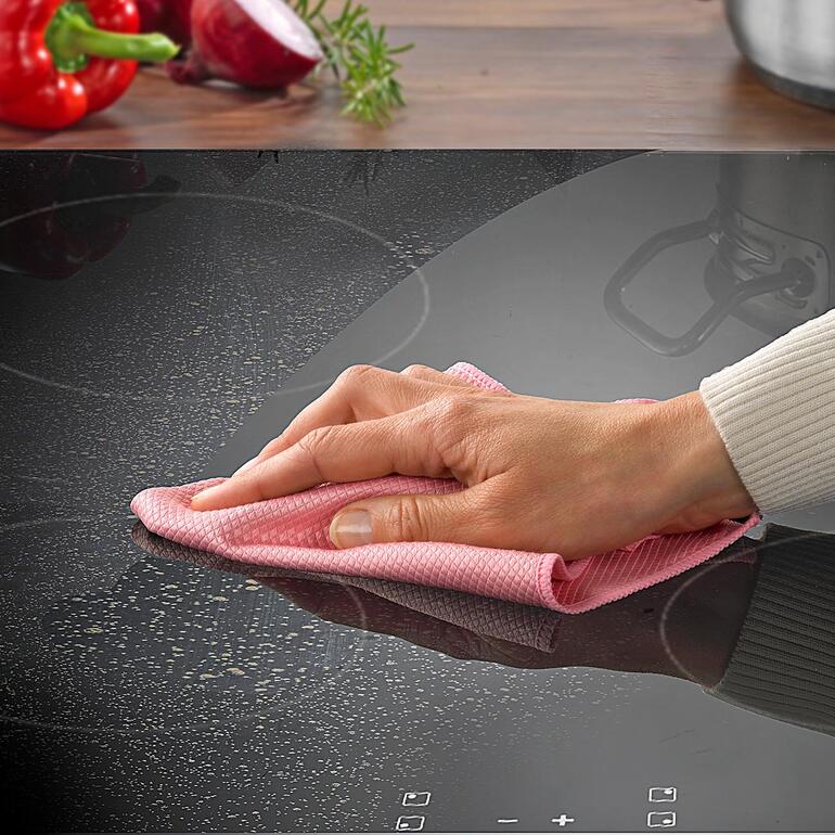 Main essuie une plaque de cuisson avec un chiffon anti-graisse.