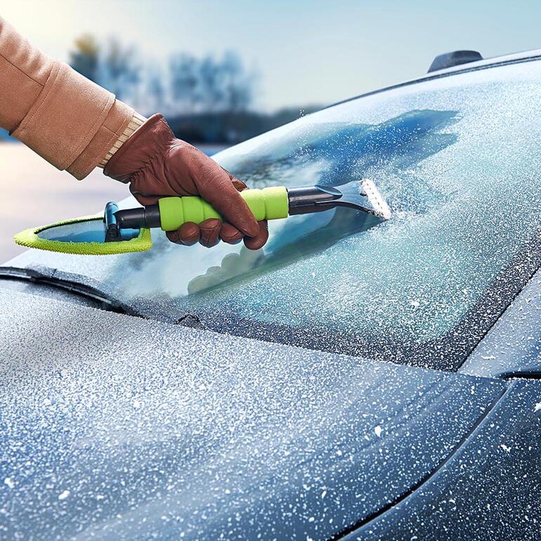 Main tenant un nettoyeur de vitres combiné enlevé le givre du pare-brise