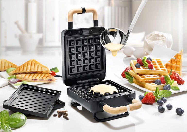 Appareil 2-en-1 pour gaufres et sandwiches dans une cuisine moderne, de la pâte est versée.