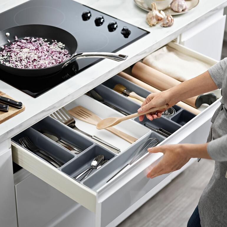 Organisateur de tiroir modulaire avec différents compartiments dans une cuisine.