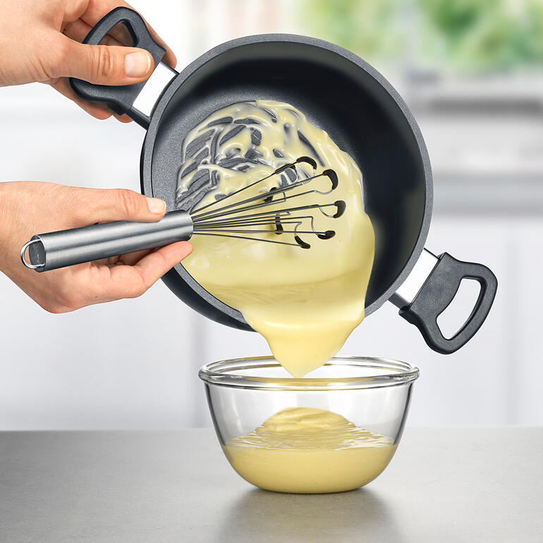 Vous atteignez tous les ingrédients, sans laisser de résidus, jusquʼaux recoins du fond de votre saladier. Main versant la pâte d'une casserole dans un bol