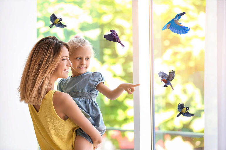 Mère avec enfant devant une fenêtre avec des autocollants d'oiseaux