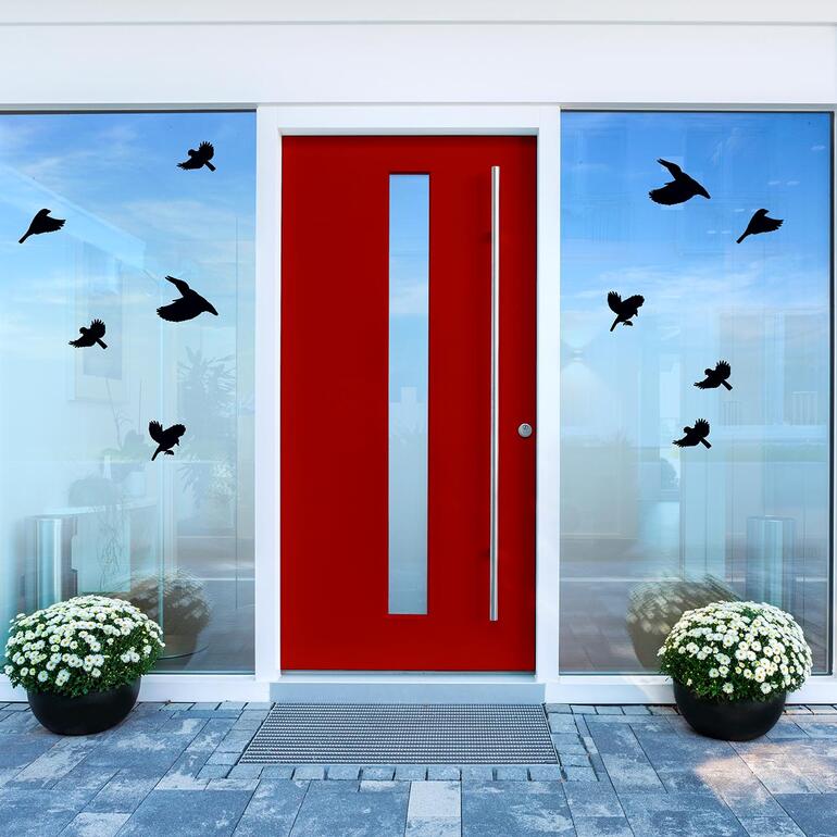 Porte rouge avec des autocollants d'oiseaux noirs sur les fenêtres