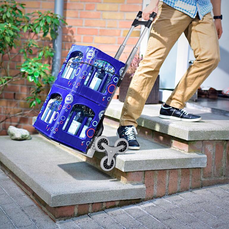 Homme avec un chariot pliable transportant deux caisses de boissons