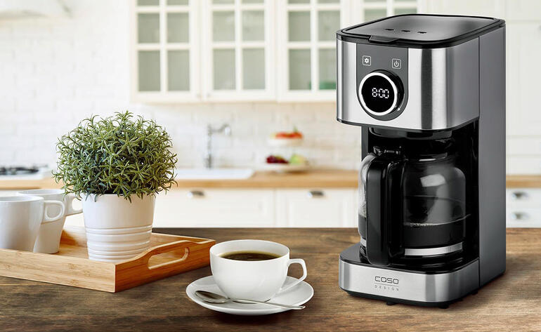 Machine à café design sur table avec café et plante.