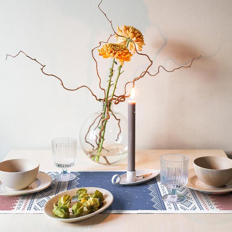 Table avec chemin de table Norvège, bougie et arrangement floral.