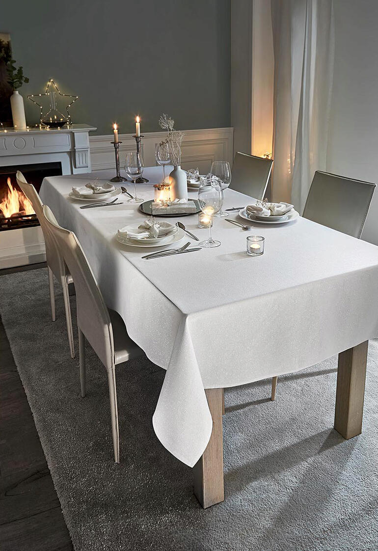 Table blanche avec nappe festive en aspect lin et bougies.