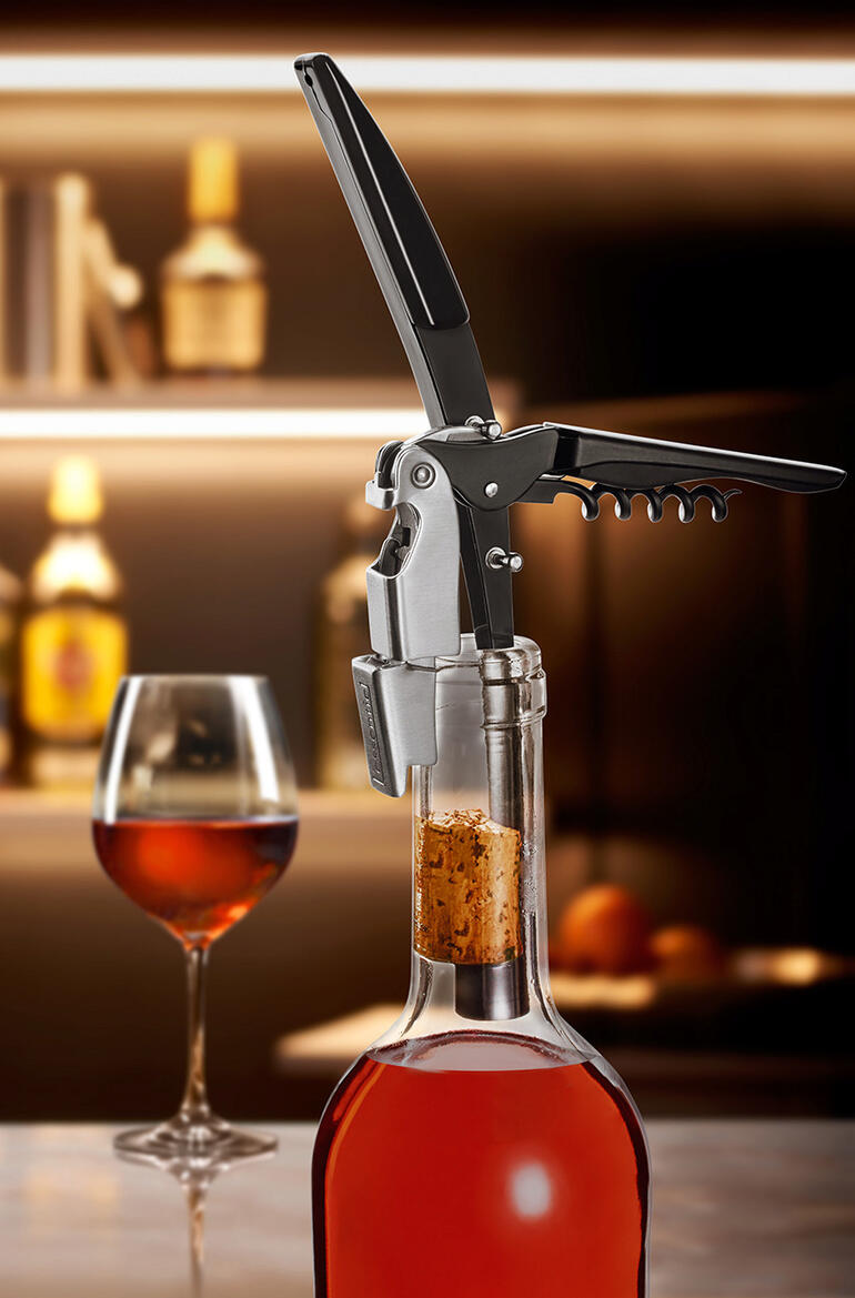 Bouteille de vin avec tire-bouchon, placée sur une table dans un environnement de restaurant.