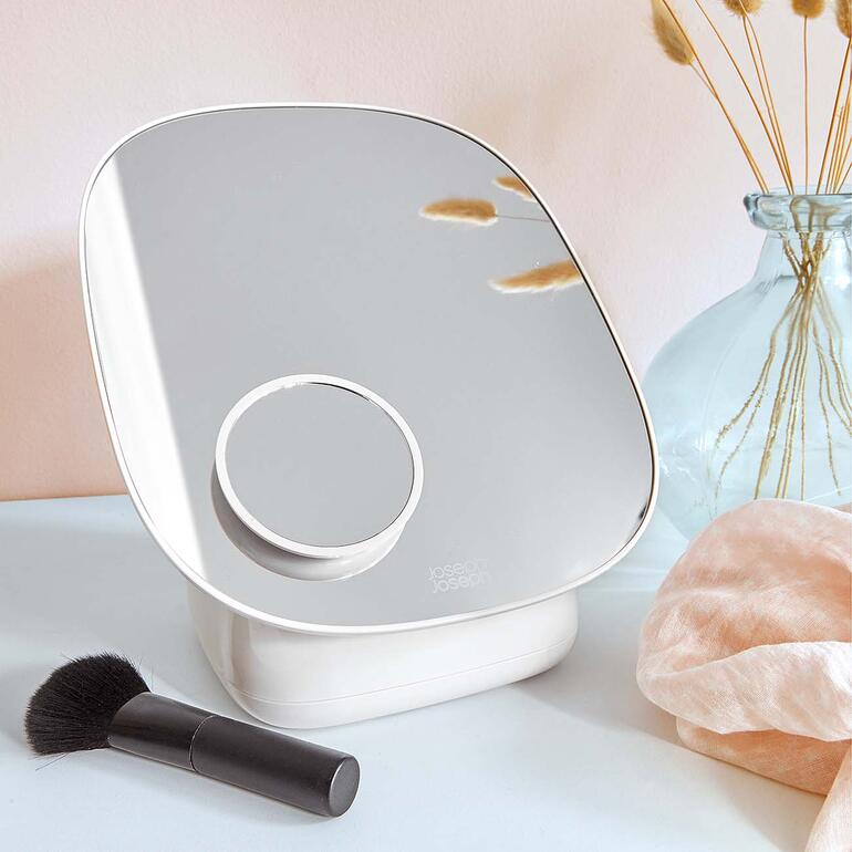 Miroir de maquillage avec grand miroir et base ronde posé sur une table.