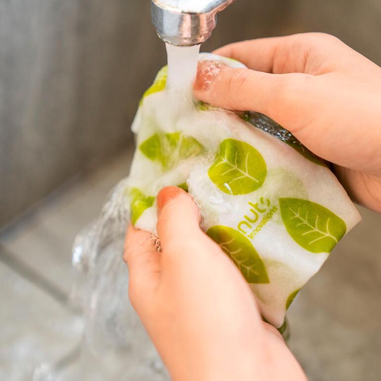 Mains lavant l'essuie-tout réutilisable sous l'eau