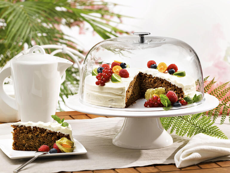 Cloche à gâteau avec un gâteau et des fruits sur une table