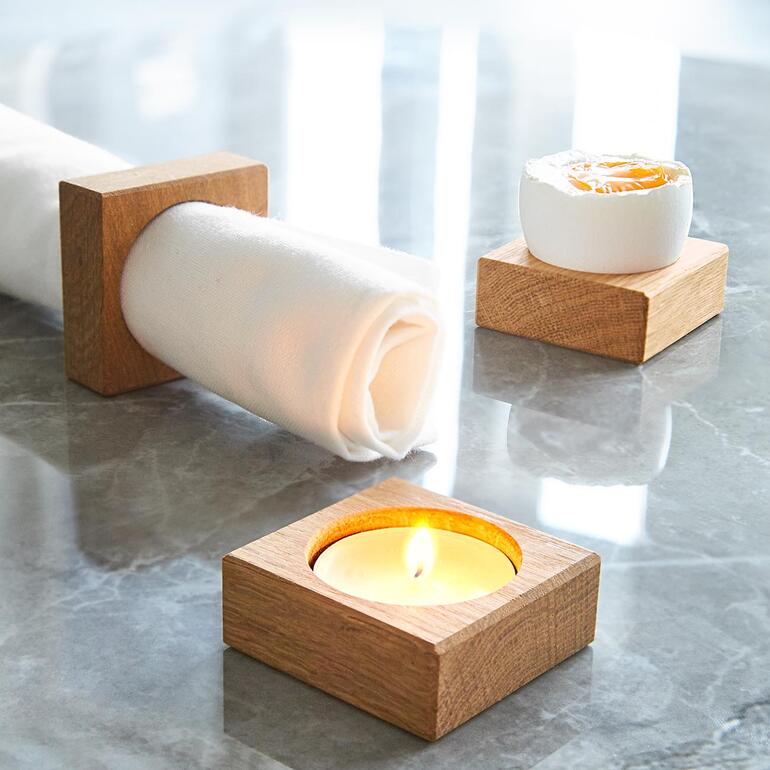 Chêne clair Ronds de serviette en bois et bougie sur une surface de table marbrée