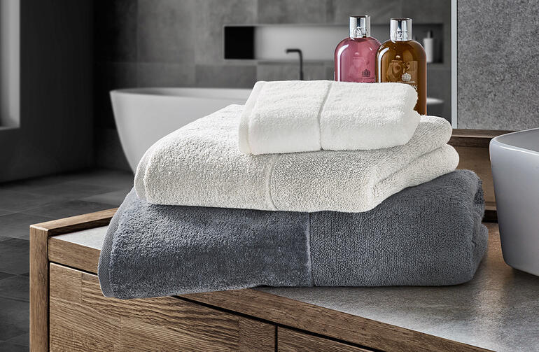 Serviettes de bain claires en blanc et gris sur un meuble de salle de bain