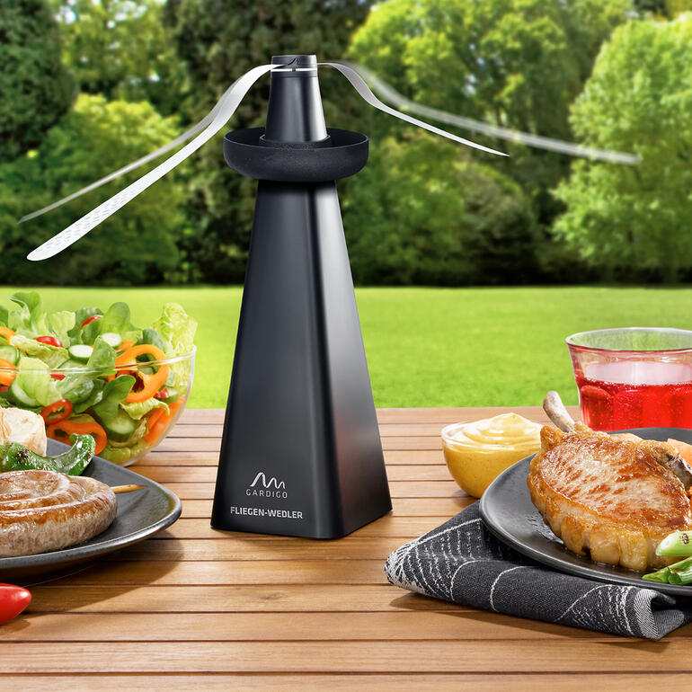 Éloigneur de mouches avec répulsif à guêpes sur une table avec des plats grillés.