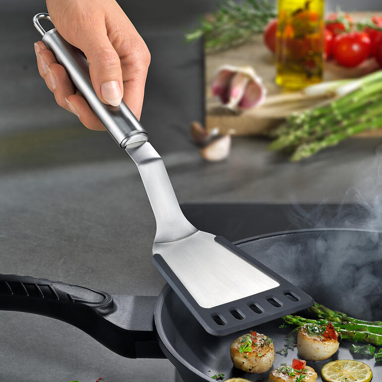 Spatule inclinée utilisée pour retourner les aliments dans une poêle.