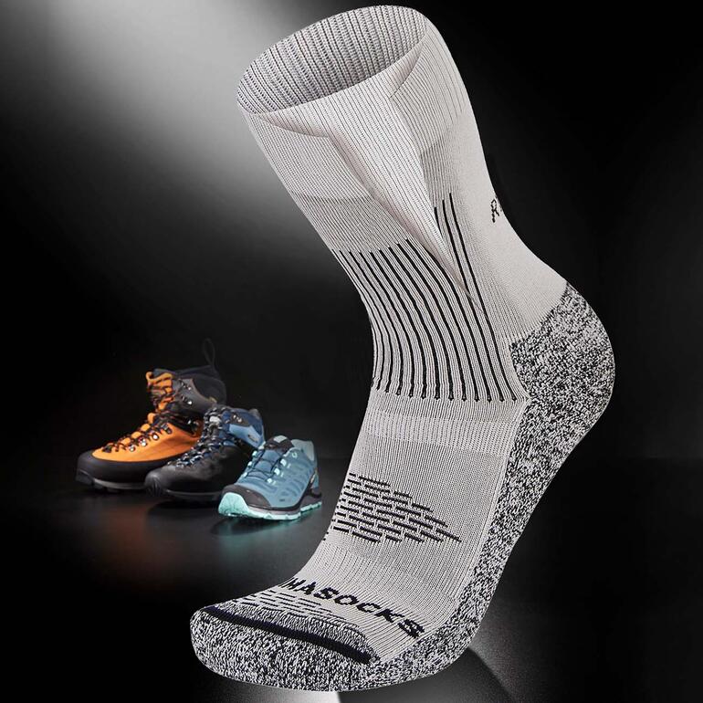 Chaussette antibulles sur fond noir avec des chaussures de montagne en arrière-plan.