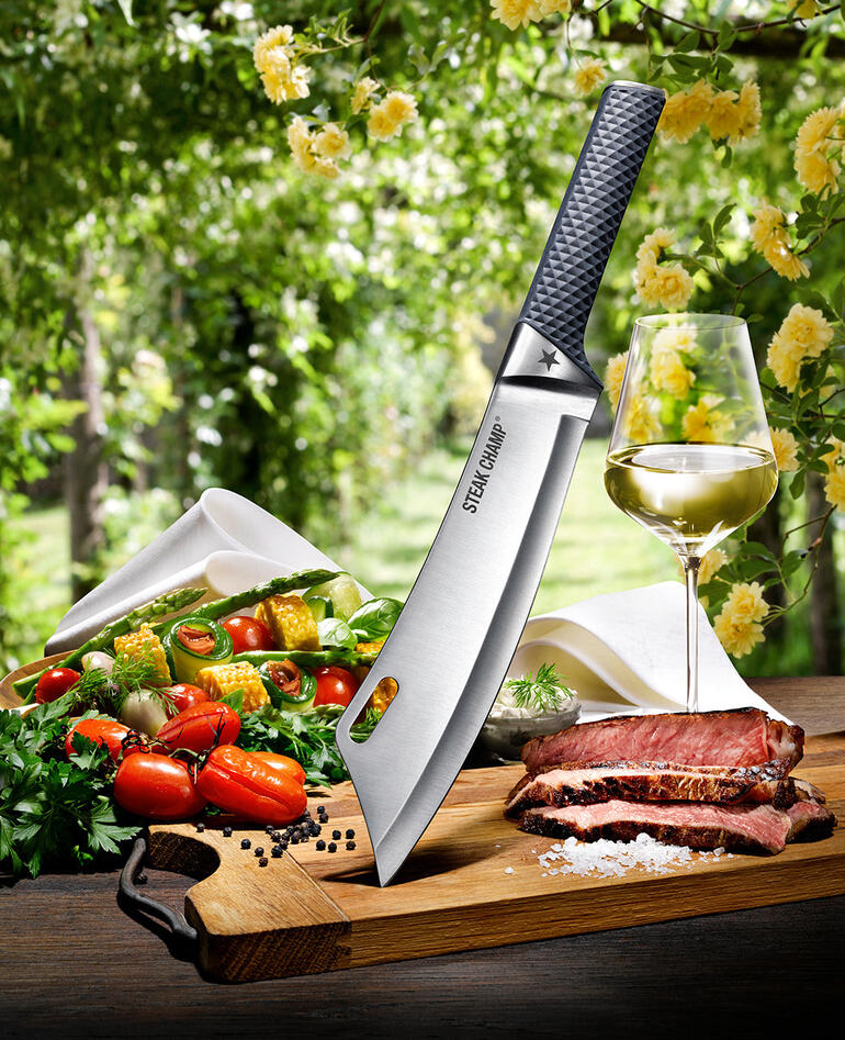 Couteau de cuisine SteakChamp vu du dessus, entouré de légumes et de viande sur une planche à découper.