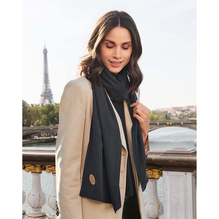 L’écharpe de voyage douce et douillette est une bonne protection contre les courants d’air. Femme portant une écharpe de voyage avec la silhouette de Paris et la Tour Eiffel.