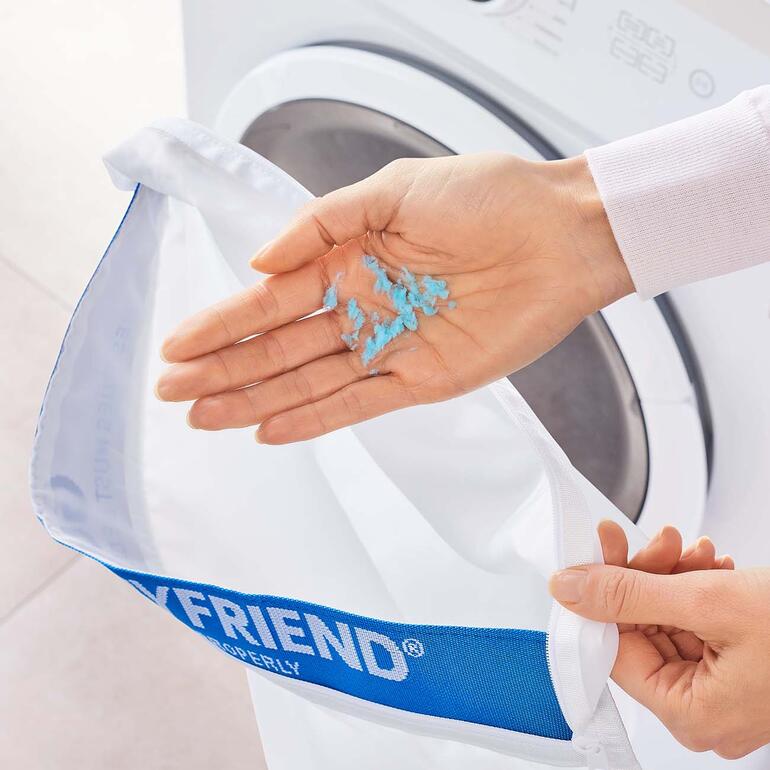 Les fibres de plastique, qui ont rompues, se nichent dans un coin du sac à linge et peuvent être enlevées. Retrait manuel de microplastiques du sac STOP! à linge