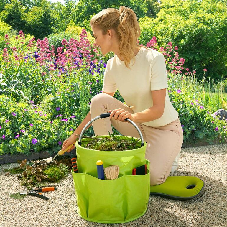 Femme en train de planter avec un jardin Caddy dans un jardin coloré.