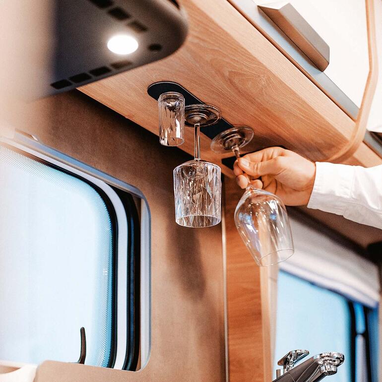 Main prenant un verre en cristal suspendu dans un camping-car