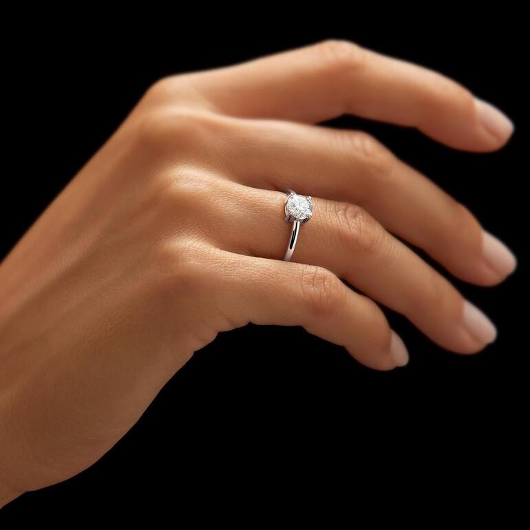 Gros plan d'une bague en Moissanite rhodiée au doigt d'une personne.