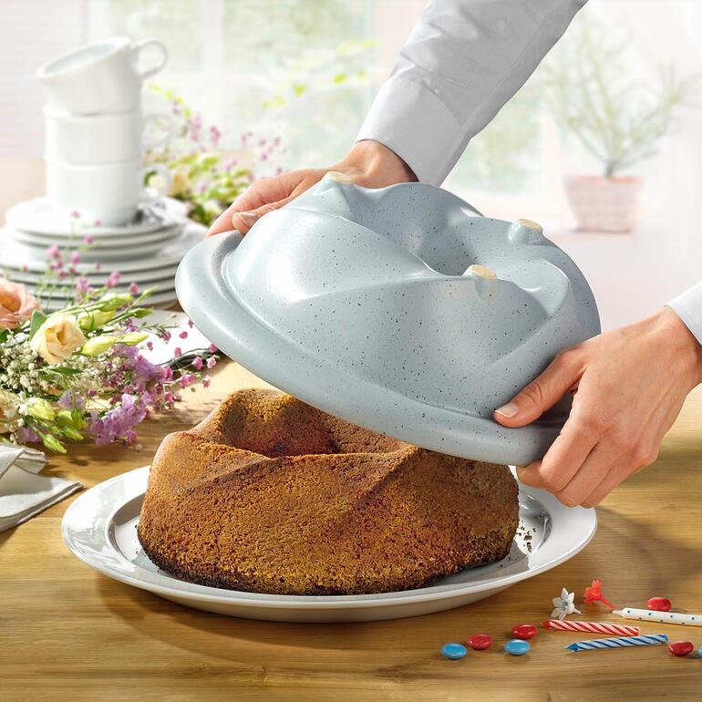 Cuisinier montrant le moule à Gugelhupf CeraFlam avec gâteau fraîchement cuit.