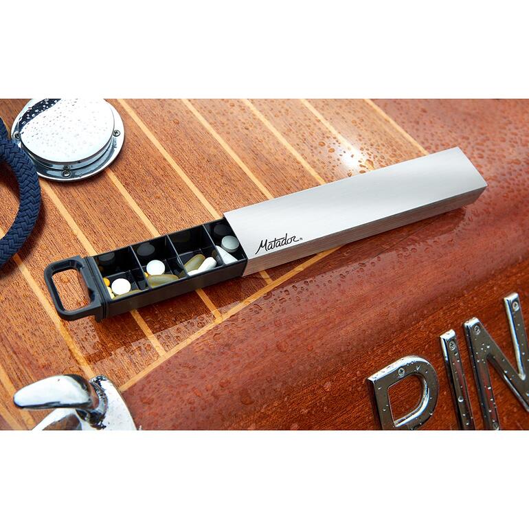 Boîte à pilules étanche sur une table en bois de bateau avec divers comprimés.