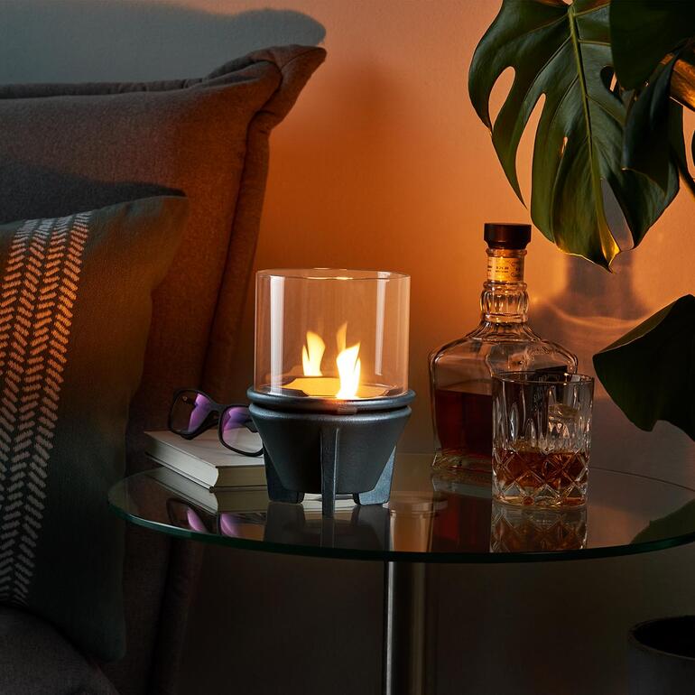 Feu de fusion avec un cylindre en verre sur une table à côté de whiskey et de plantes.