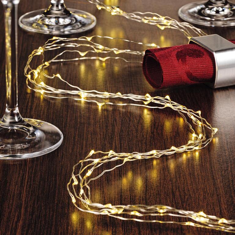 La guirlande lumineuse « cheveux d’ange » est entièrement flexible, facile à mettre en forme et aux multiples facettes. Guirlande de lumières en cheveux d'ange sur une table avec des verres à vin.