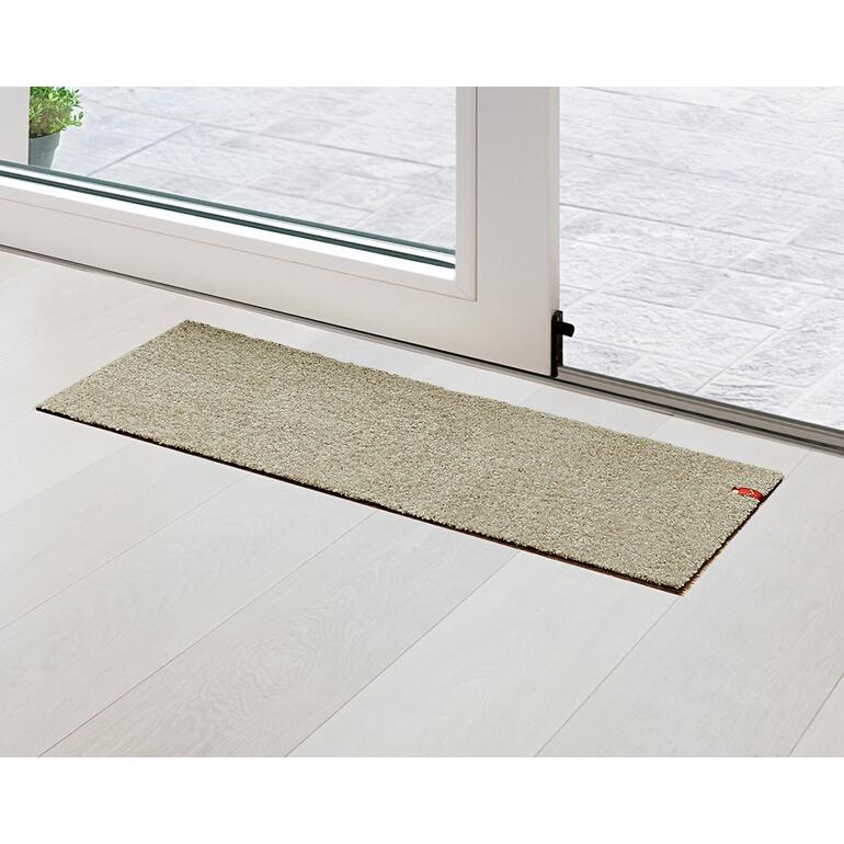 Greige Tapis de porte de terrasse beige devant une porte vitrée.