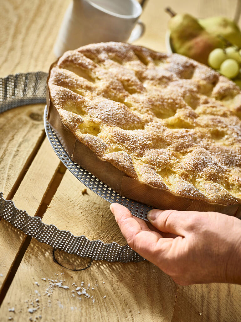 Moule en acier inoxydable perforé avec un gâteau fraîchement cuit.