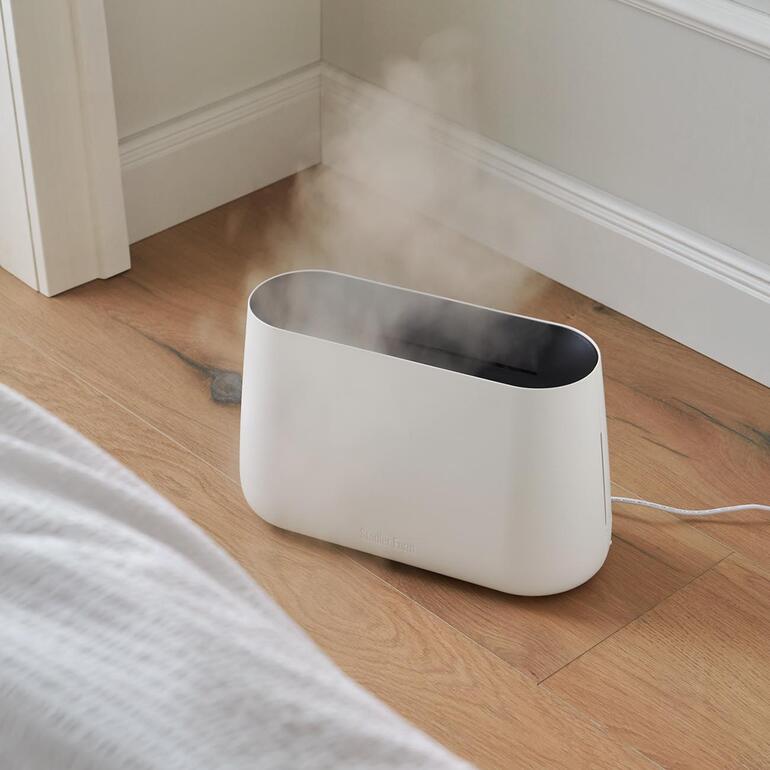 Blanc Humidificateur 3-en-1 BEN en fonctionnement avec de la vapeur dans une chambre.