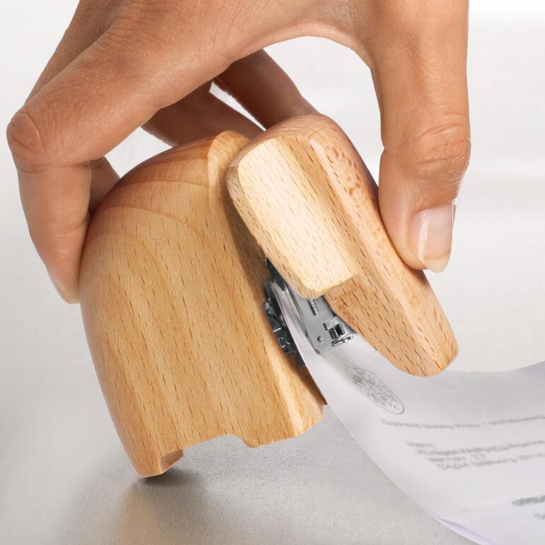 Agrafeuse éléphant Main tenant des papiers tout en utilisant une agrafeuse en bois en forme d'éléphant.