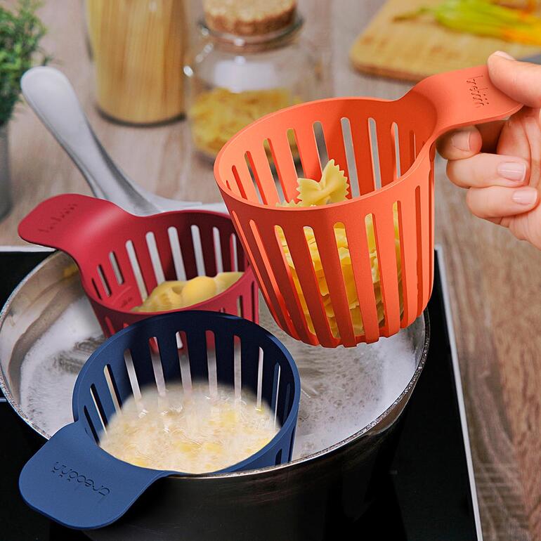 Trois paniers de cuisson de différentes couleurs, l'un est tenu au-dessus d'une casserole.