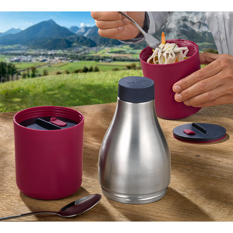 Conteneur à lunch 2-en-1 et bouteille de boisson, utilisés dans un paysage montagneux.