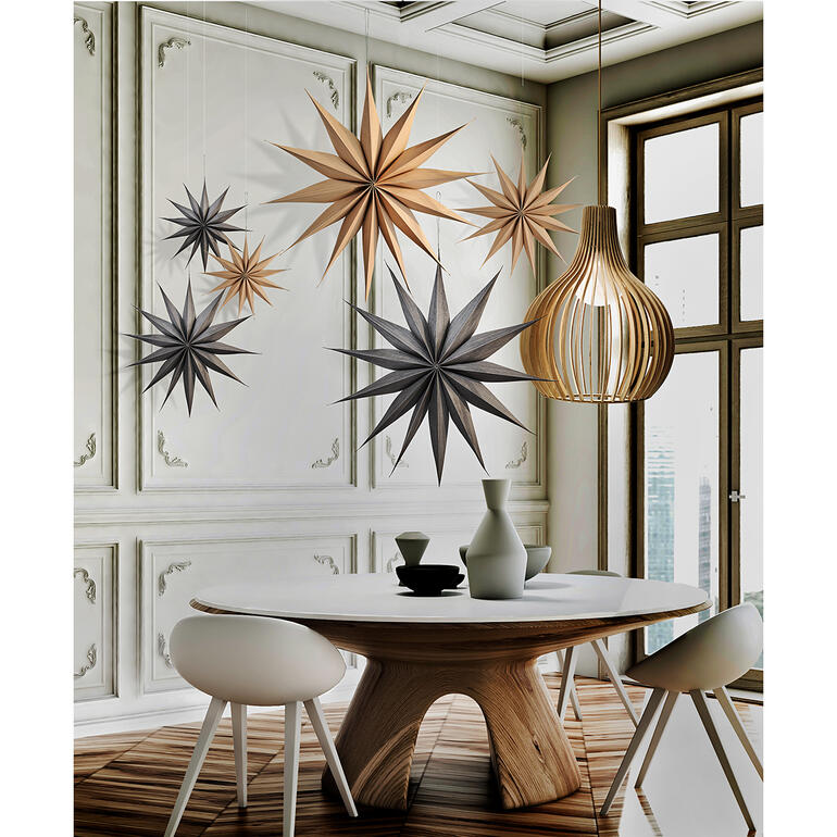Disponible en 3 tailles (ici en taille S et L) et 2 couleurs. Des étoiles de Noël en bois suspendues au-dessus d'une table dans une pièce moderne.