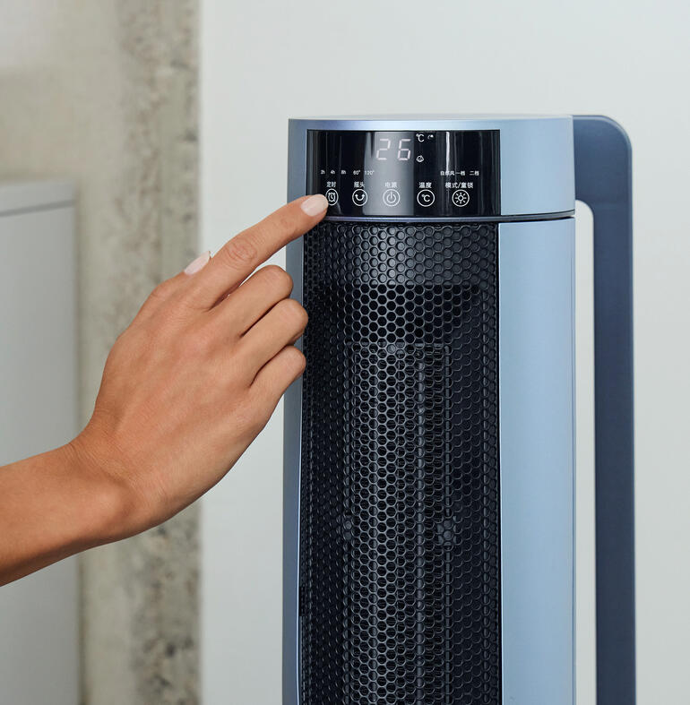 Main sur le panneau de commande du radiateur céramique PTC avec affichage de la température