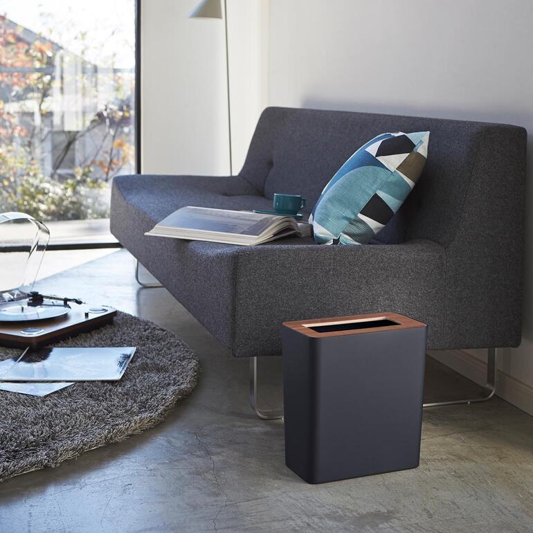 Poubelle noire à côté d'un canapé dans une pièce moderne.