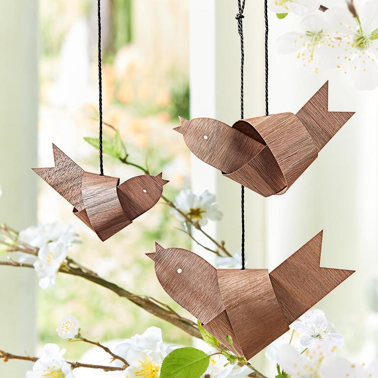 Trois oiseaux en bois noués suspendus à une branche