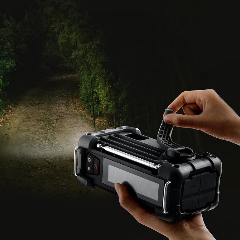 Main sur une radio de survie numérique avec lumière dans un environnement sombre.
