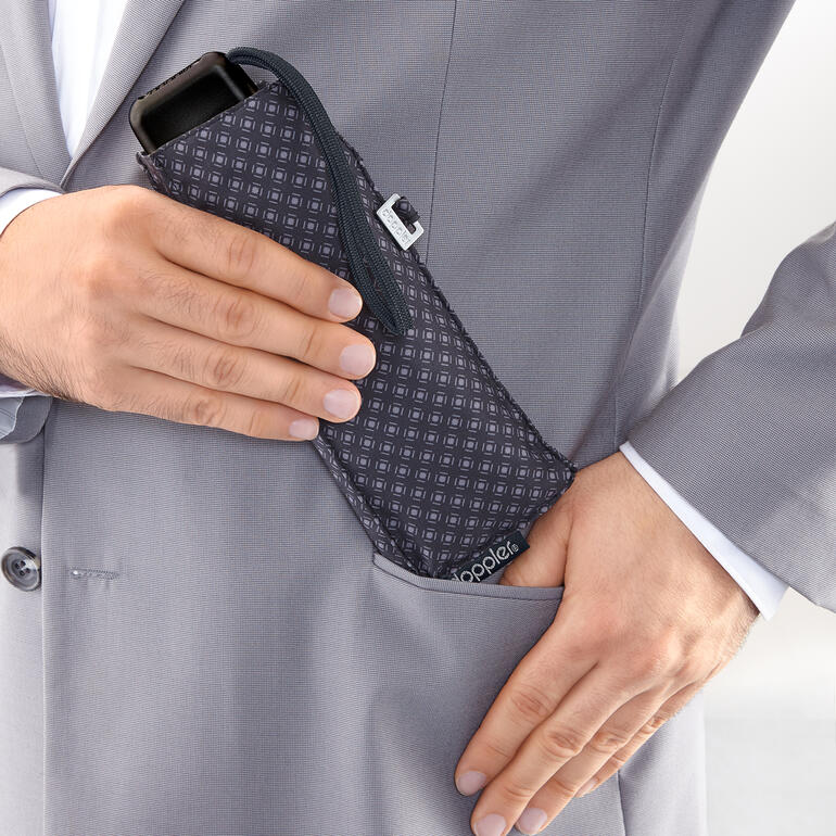 Mains mettant un parapluie de poche en acier au carbone dans une poche de costume.