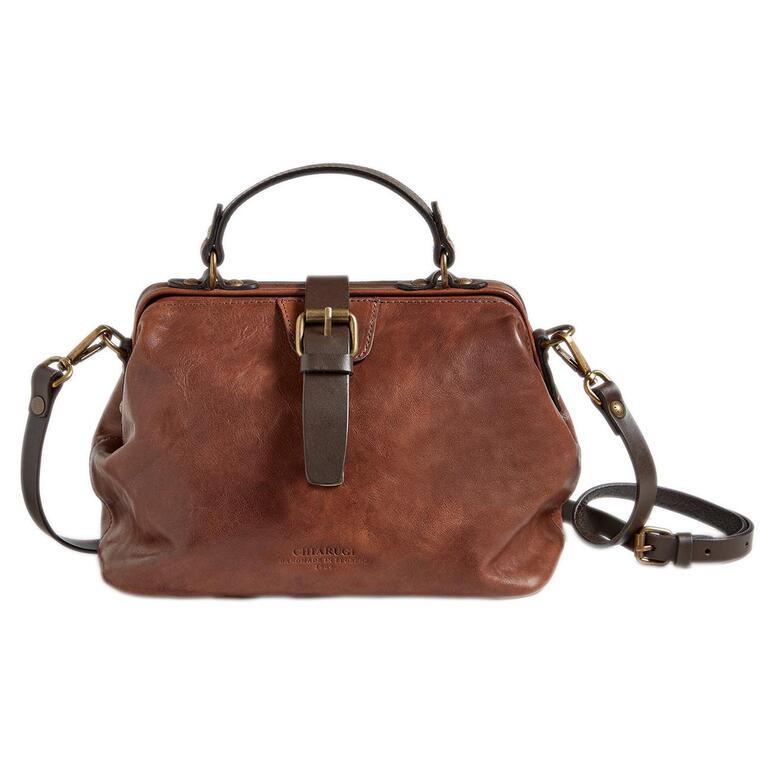 Le cuir est encore apprêté de manière traditionnelle en l’astiquant avec des rouleaux en ambre. Il devient ainsi agréable au toucher et le grain ressort de manière expressive. Sac médecin marron sur un fond blanc