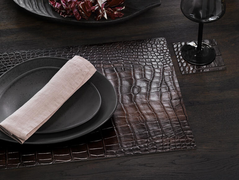 Table dressée avec set crocodile et sous-verres, servi avec de la vaisselle.