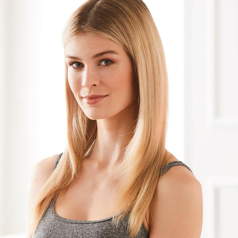 Vous réussissez vos coiffures parfaitement et très facilement, que vous boucliez ou lissiez vos cheveux. Femme aux cheveux lisses souriant à la caméra.