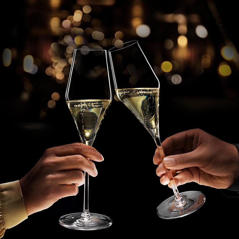 En soulevant les verres, une lumière met en scène le jeu de perles pétillantes dans le calice de manière spectaculaire. Deux flûtes à champagne lumineuses se trinquent