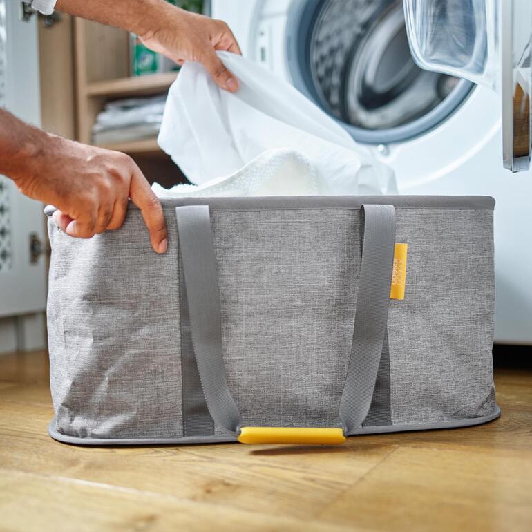 Panier à linge pliable en cours d'utilisation en le remplissant de linge