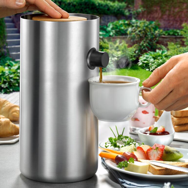 Cafetière design en acier inoxydable à côté d'une tasse à café.